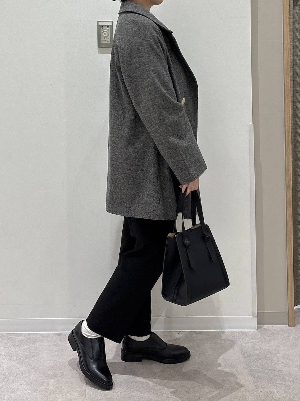 ブラック系のショルダーバッグ、グレー系のチェスターコート、ブラック系のその他パンツを着用したレディースの冬コーディネートの2枚目の写真