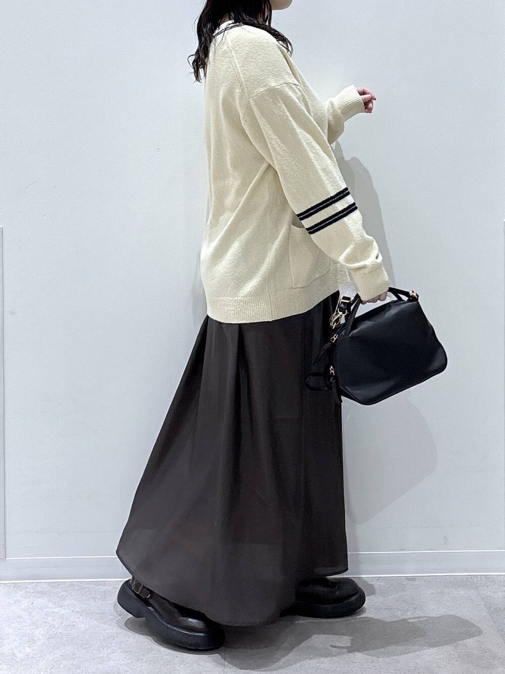 ブラック系のショルダーバッグ、ブラウン系のスカートを着用したレディースの冬コーディネートの2枚目の写真