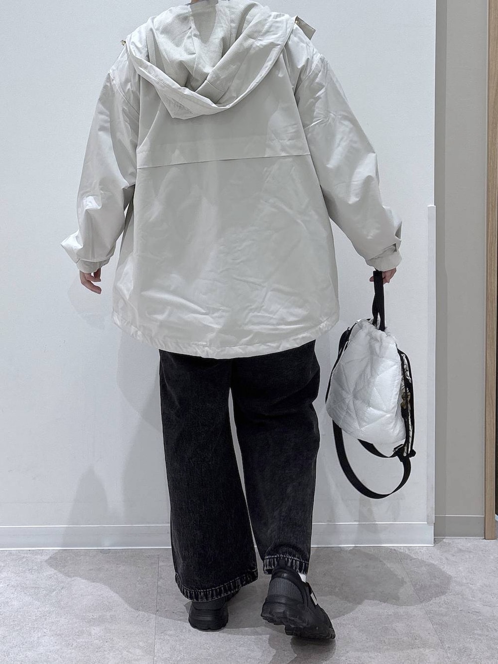 ブラック系のデニムパンツ、ホワイト系のハンドバッグ、ベージュ系のパーカーを着用したレディースの春コーディネートの3枚目の写真