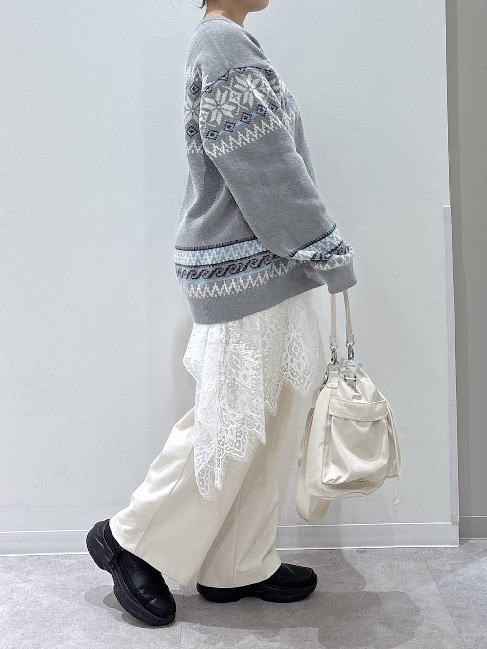 ホワイト系のショルダーバッグ、ブラック系のブーツ、グレー系のニット/セーターを着用したレディースの冬コーディネートの2枚目の写真