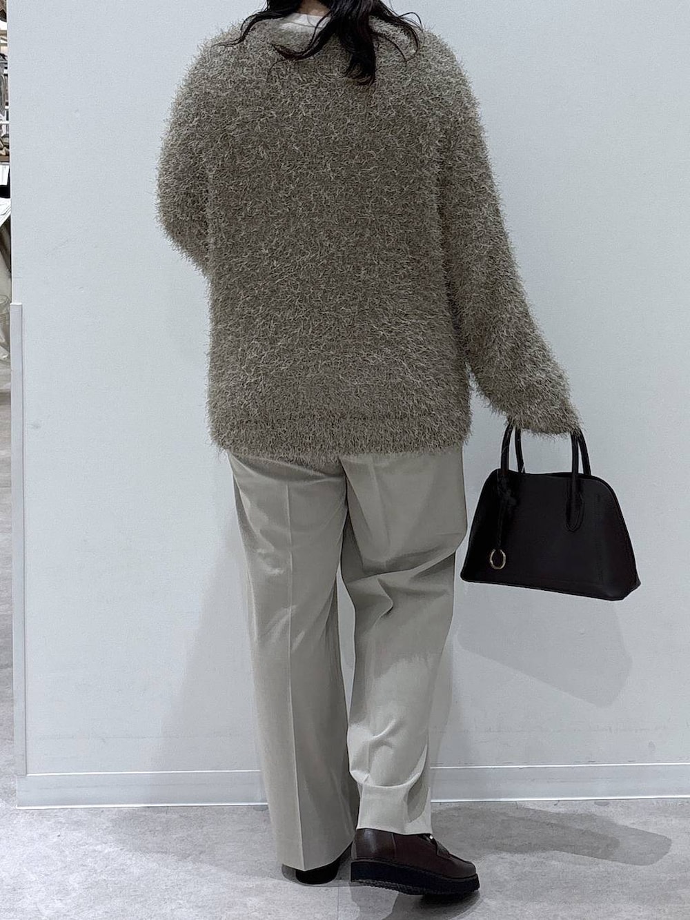 ブラウン系のローファー、ブラウン系のショルダーバッグ、ベージュ系のスラックスを着用したレディースの冬コーディネートの3枚目の写真