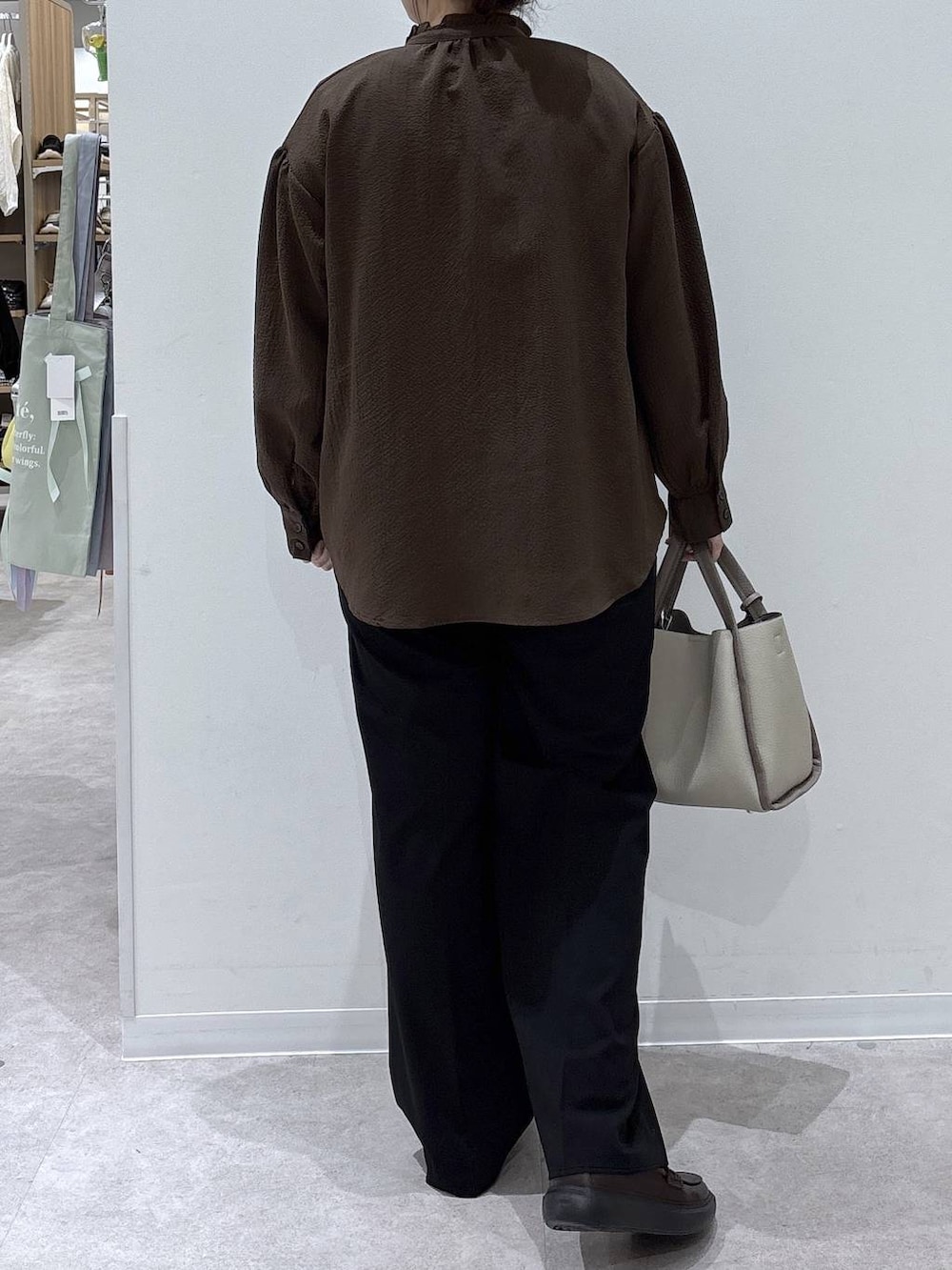 ベージュ系のトートバッグ、ブラック系のスラックス、ブラウン系のシャツ/ブラウスを着用したレディースの春コーディネートの3枚目の写真