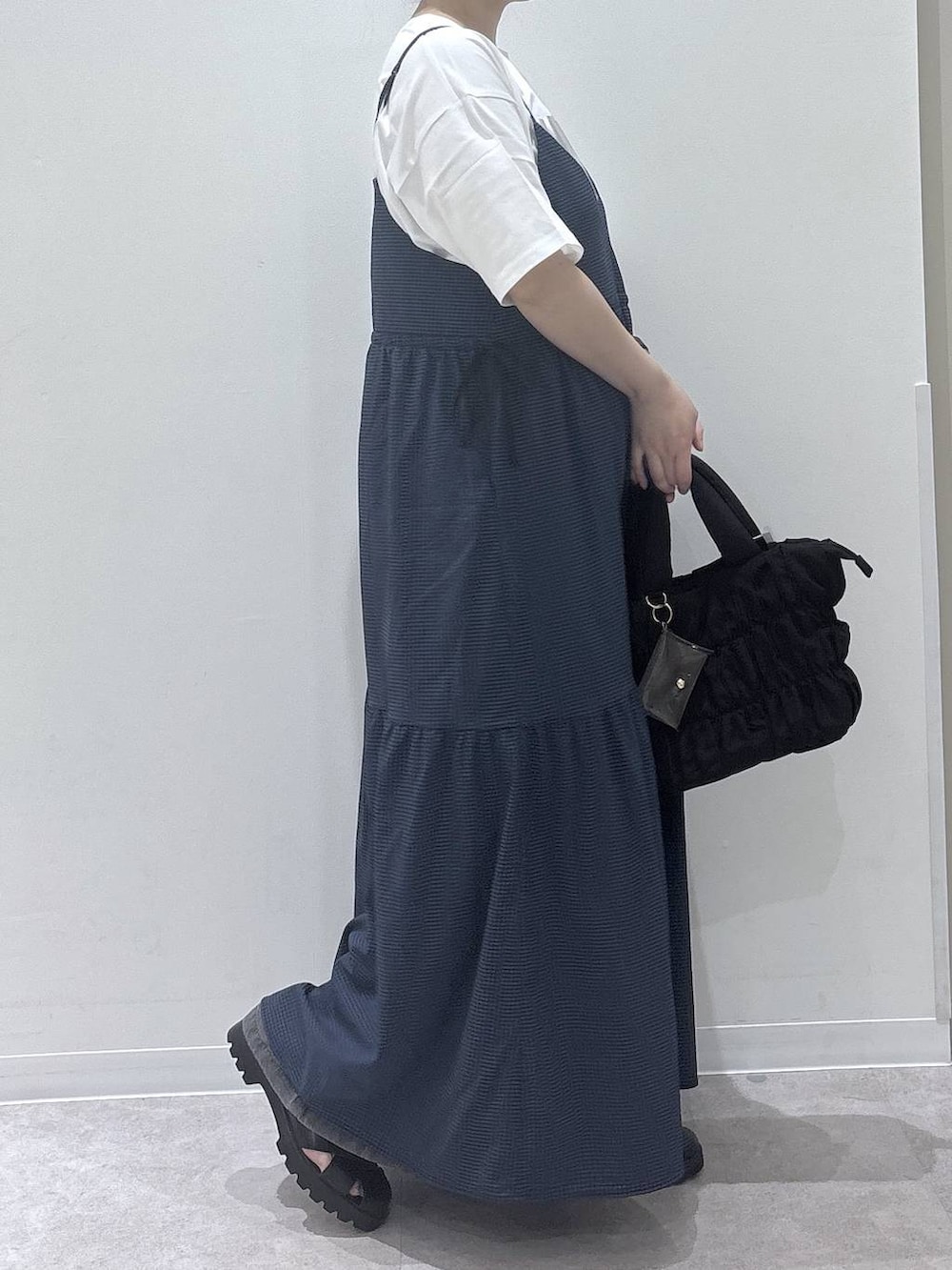 ブラック系のトートバッグ、ブルー系のワンピース、ホワイト系のTシャツ/カットソーを着用したレディースの春コーディネートの2枚目の写真