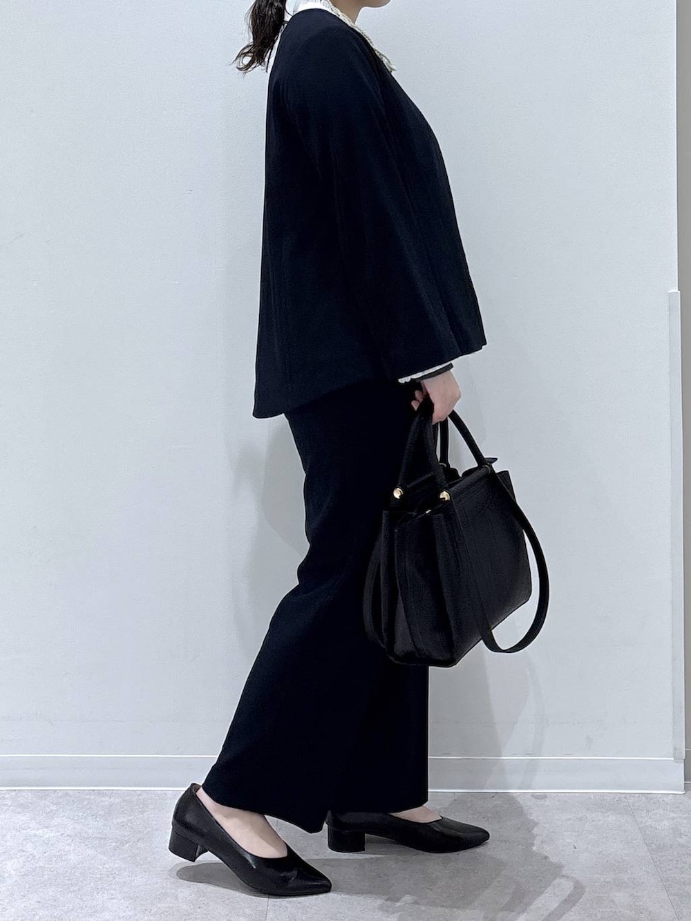 ブラック系のパンプス、ブルー系のセットアップ、ブラック系のトートバッグを着用したレディースの冬コーディネートの2枚目の写真