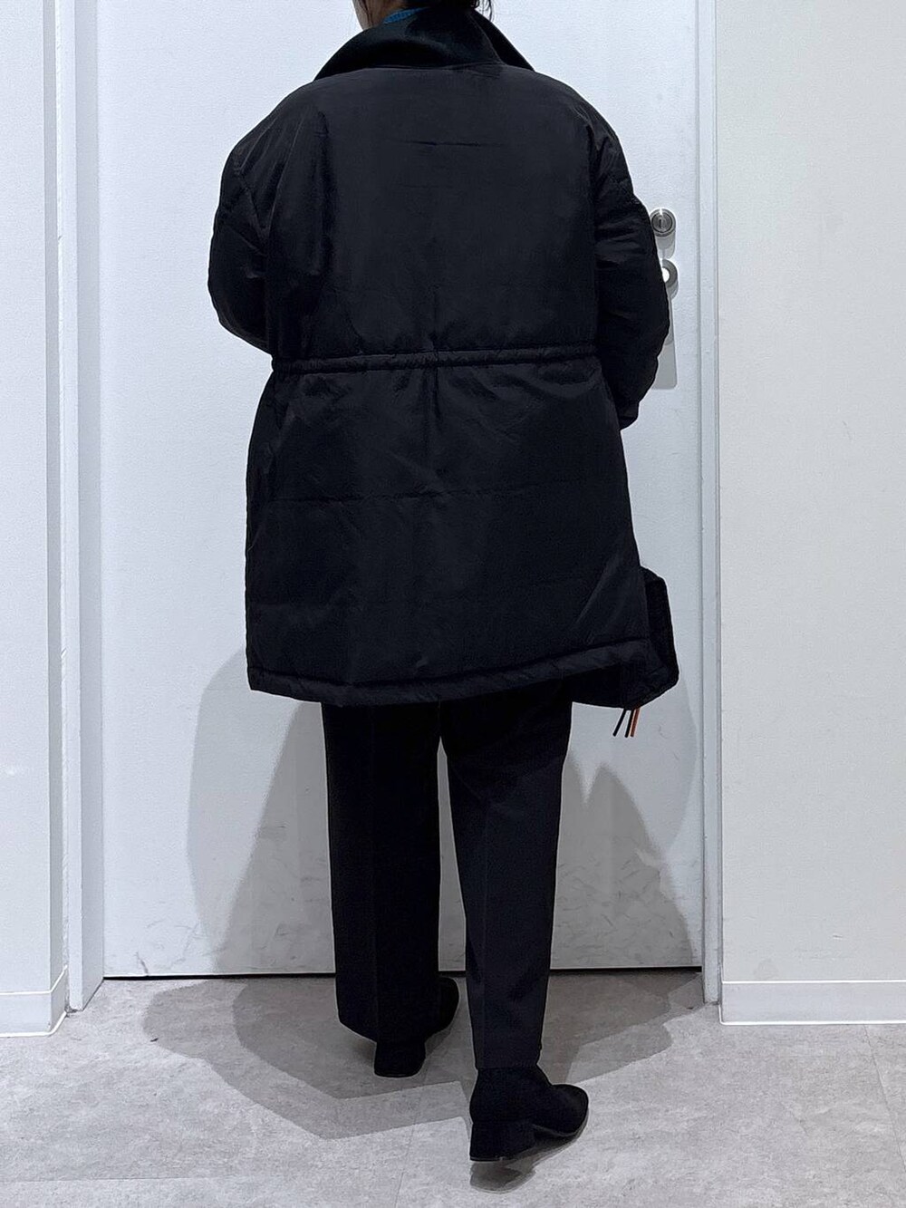 ブラック系のダウンジャケット/コート、ブラック系のボストンバッグ、ブルー系のニット/セーターを着用したレディースの冬コーディネートの3枚目の写真