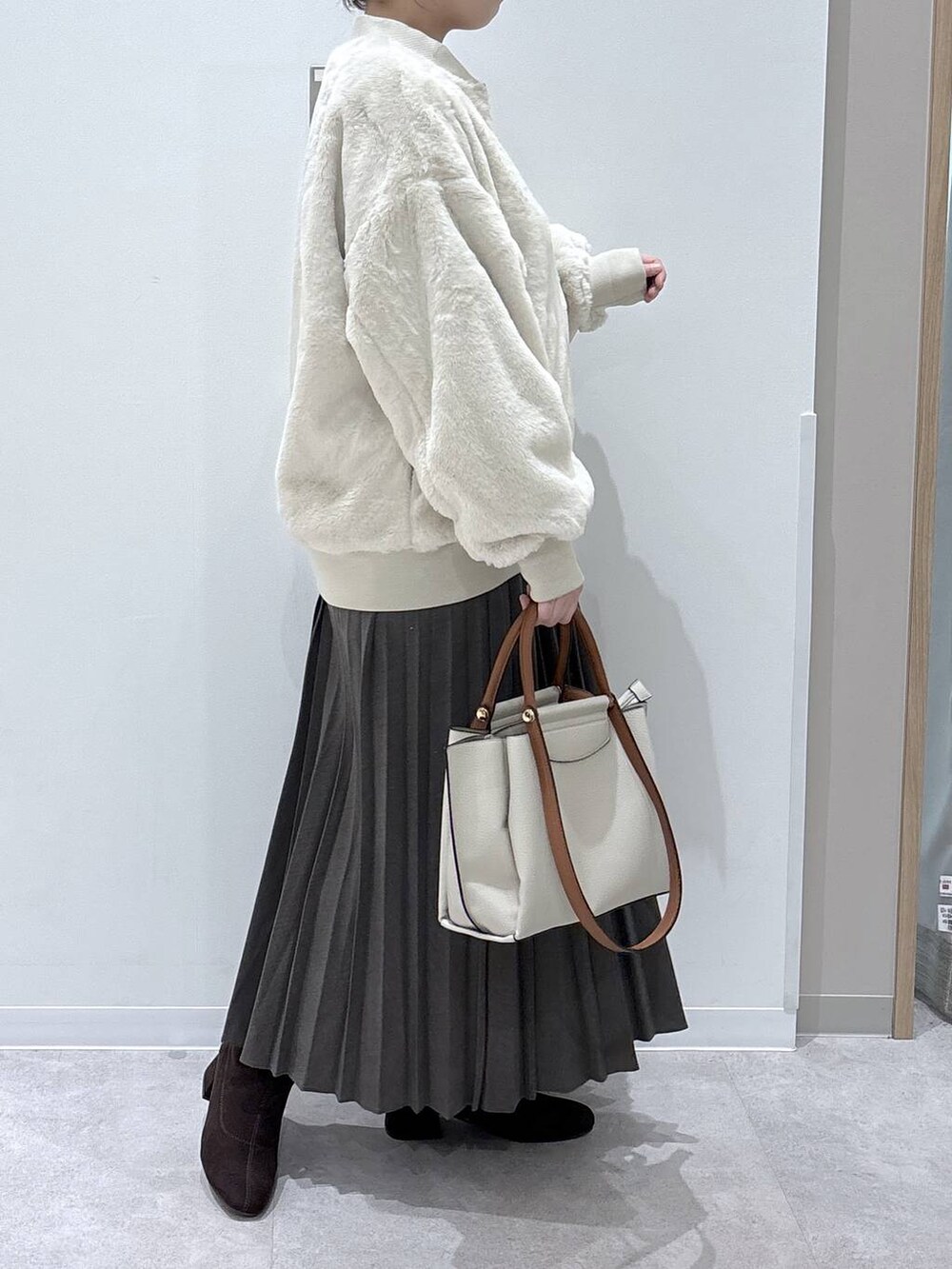 ベージュ系のブルゾン、ベージュ系のスカート、レッド系のニット/セーターを着用したレディースの冬コーディネートの2枚目の写真