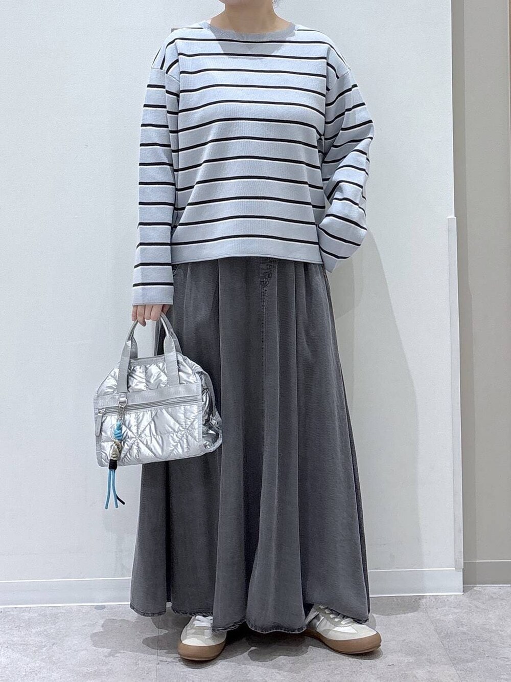 ホワイト系のスニーカー、シルバー系のボストンバッグ、ブルー系のニット/セーターを着用したレディースの春コーディネートの4枚目の写真