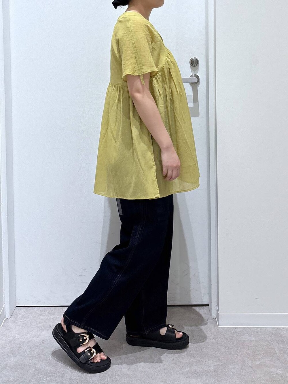 ブルー系のデニムパンツ、イエロー系のシャツ/ブラウス、ブラック系のサンダルを着用したレディースの夏コーディネートの2枚目の写真