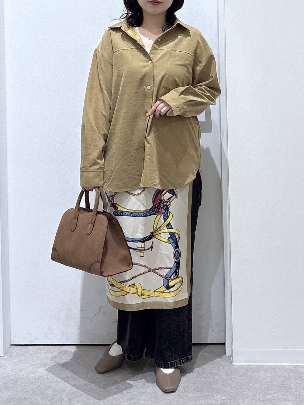 ブラック系のデニムパンツ、イエロー系のシャツ/ブラウス、ベージュ系のショルダーバッグを着用したレディースの秋コーディネートの4枚目の写真