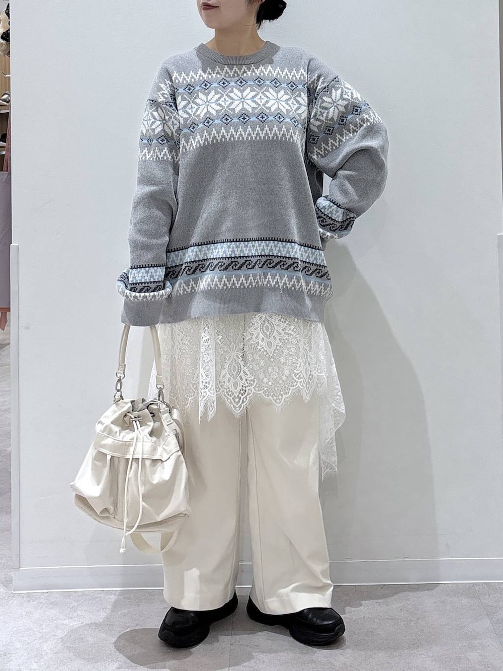 ホワイト系のショルダーバッグ、ブラック系のブーツ、グレー系のニット/セーターを着用したレディースの冬コーディネートの3枚目の写真