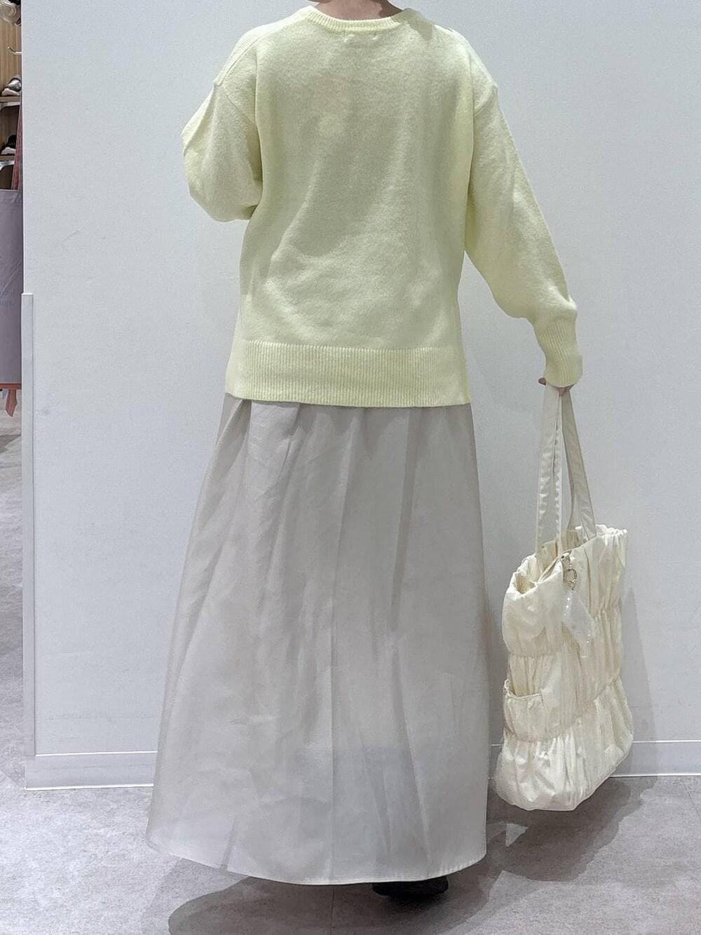 ベージュ系のトートバッグ、イエロー系のニット/セーター、ブラック系のブーツを着用したレディースの冬コーディネートの3枚目の写真