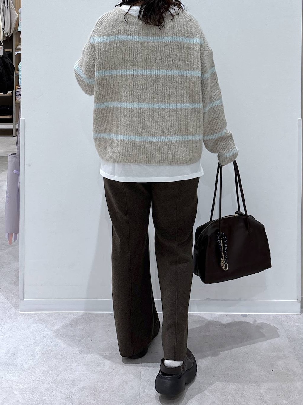 ブラウン系のボストンバッグ、ホワイト系のTシャツ/カットソー、ベージュ系のニット/セーターを着用したレディースの秋コーディネートの3枚目の写真