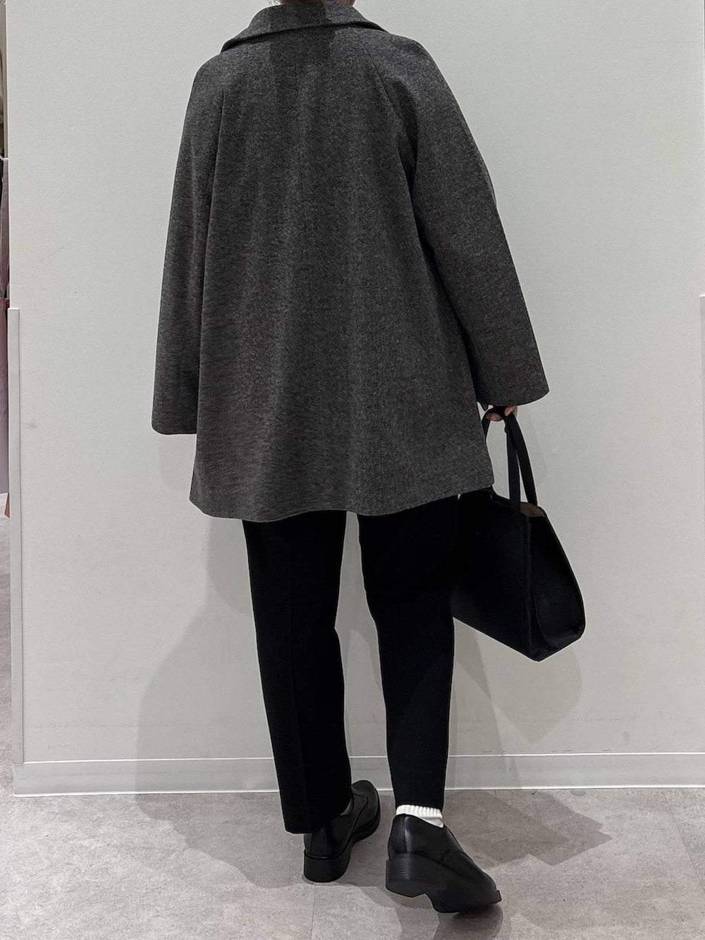 ブラック系のショルダーバッグ、グレー系のチェスターコート、ブラック系のその他パンツを着用したレディースの冬コーディネートの3枚目の写真