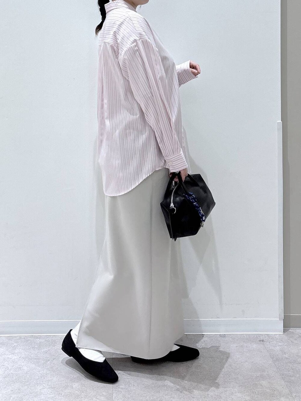 ブラック系のパンプス、ピンク系のシャツ/ブラウス、グレー系のスカートを着用したレディースの春コーディネートの2枚目の写真