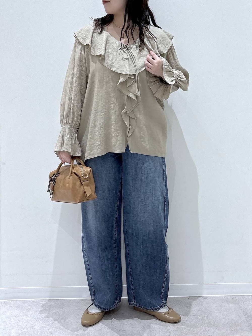 ブラウン系のバレエシューズ、ブルー系のデニムパンツ、ブラウン系のボストンバッグを着用したレディースの春コーディネートの4枚目の写真