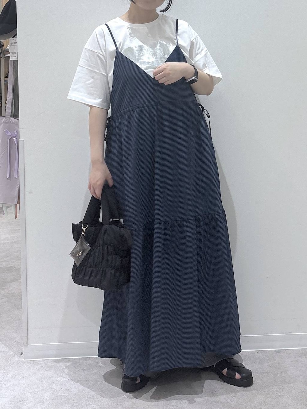 ブラック系のトートバッグ、ブルー系のワンピース、ホワイト系のTシャツ/カットソーを着用したレディースの春コーディネートの4枚目の写真