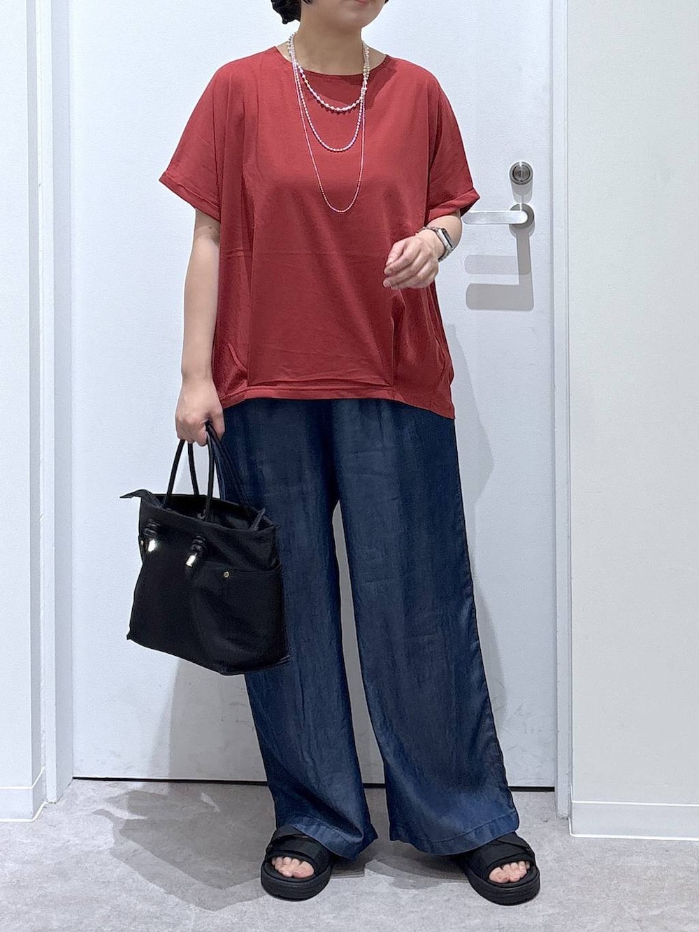 ブラック系のトートバッグ、ブラック系のサンダル、ブルー系のデニムパンツを着用したレディースの夏コーディネートの4枚目の写真