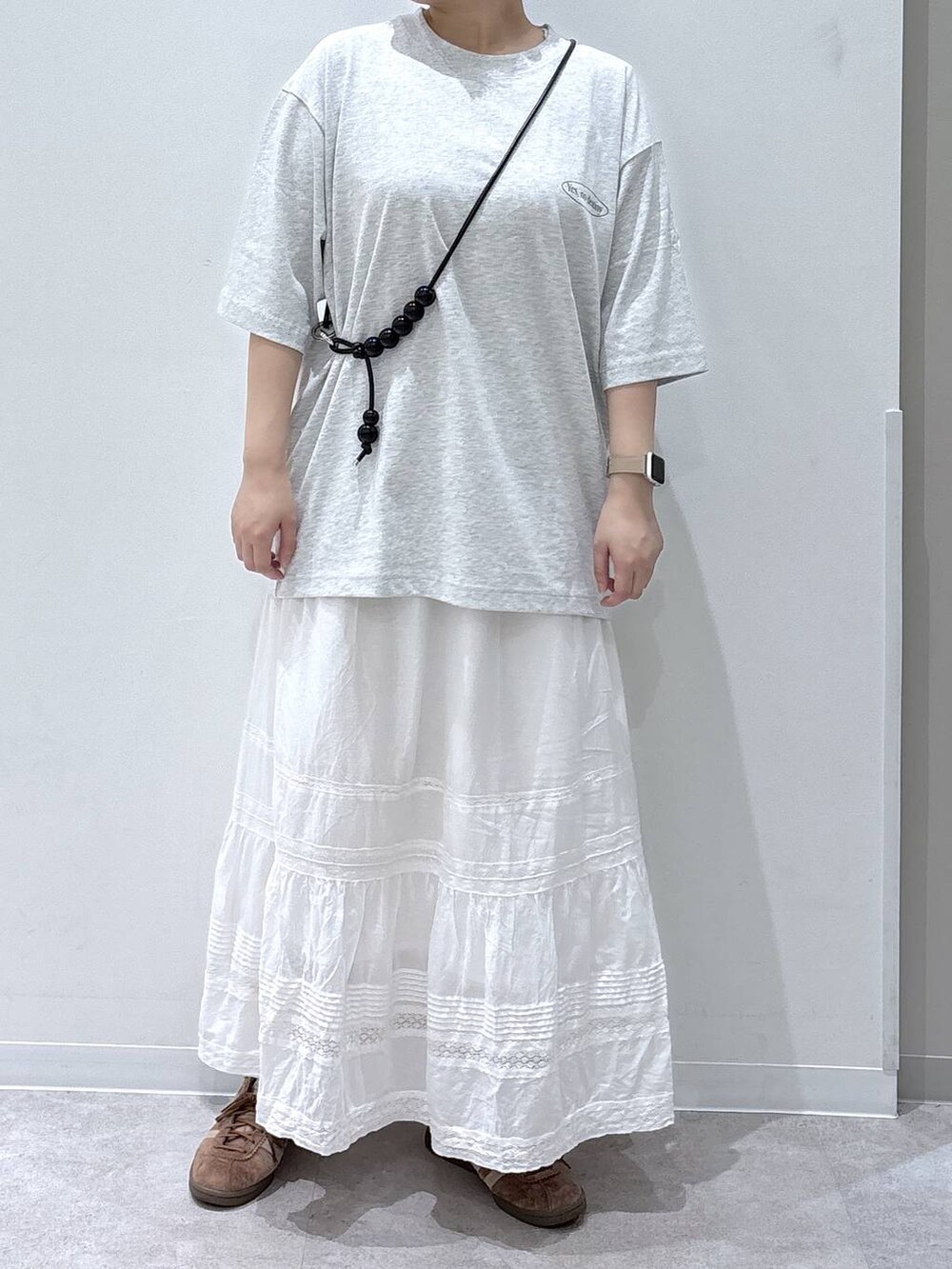 ホワイト系のスカート、グレー系のTシャツ/カットソー、ブラック系のスマホグッズを着用したレディースの夏コーディネートの4枚目の写真