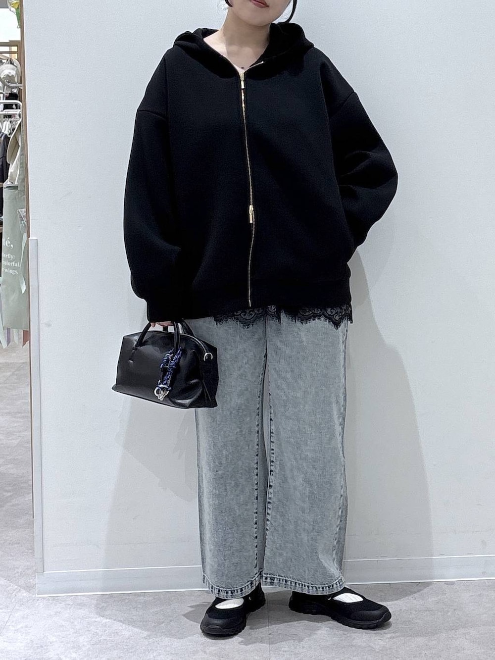 ブラック系のスニーカー、ブルー系のデニムパンツ、ブラック系のパーカーを着用したレディースの春コーディネートの4枚目の写真