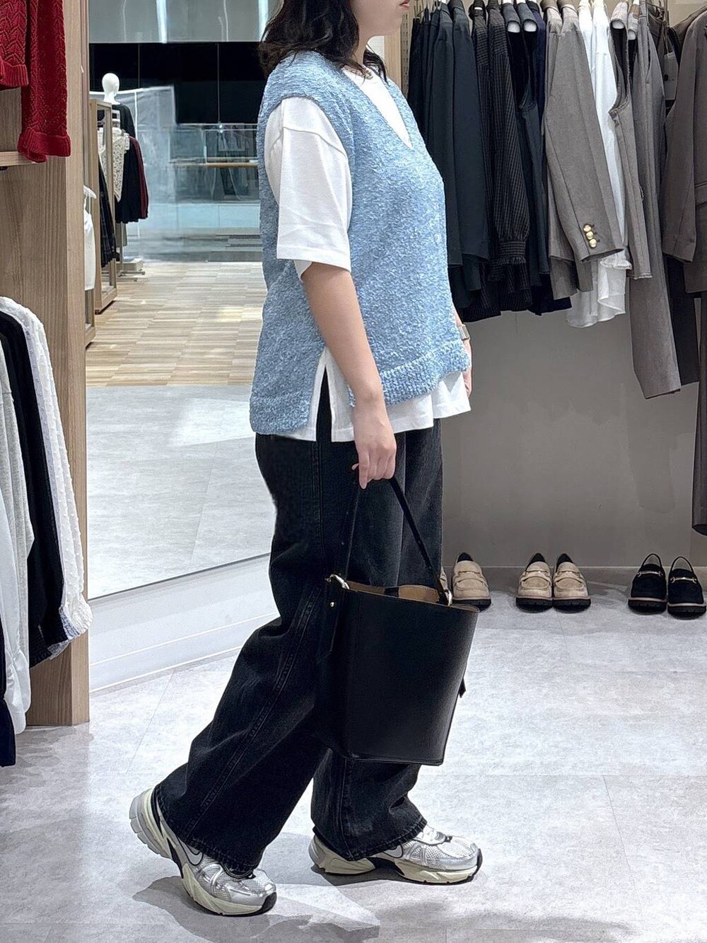 ブラック系のショルダーバッグ、ブルー系のTシャツ/カットソー、ブラック系のデニムパンツを着用したレディースの秋コーディネートの2枚目の写真