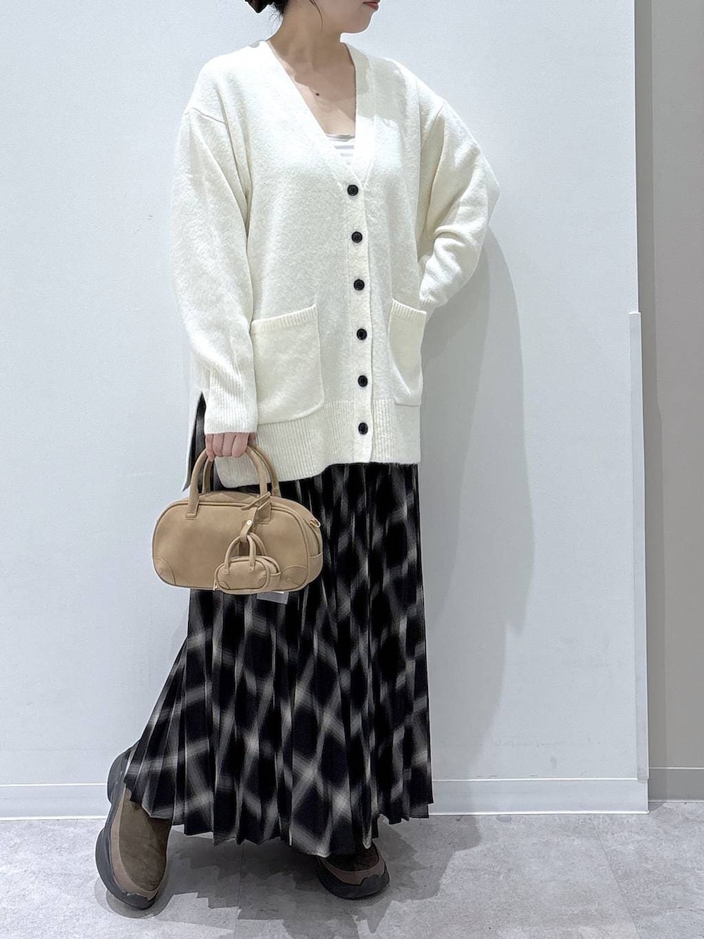 ホワイト系のカーディガン/ボレロ、ブラウン系のブーツ、ブラック系のスカートを着用したレディースの冬コーディネートの5枚目の写真