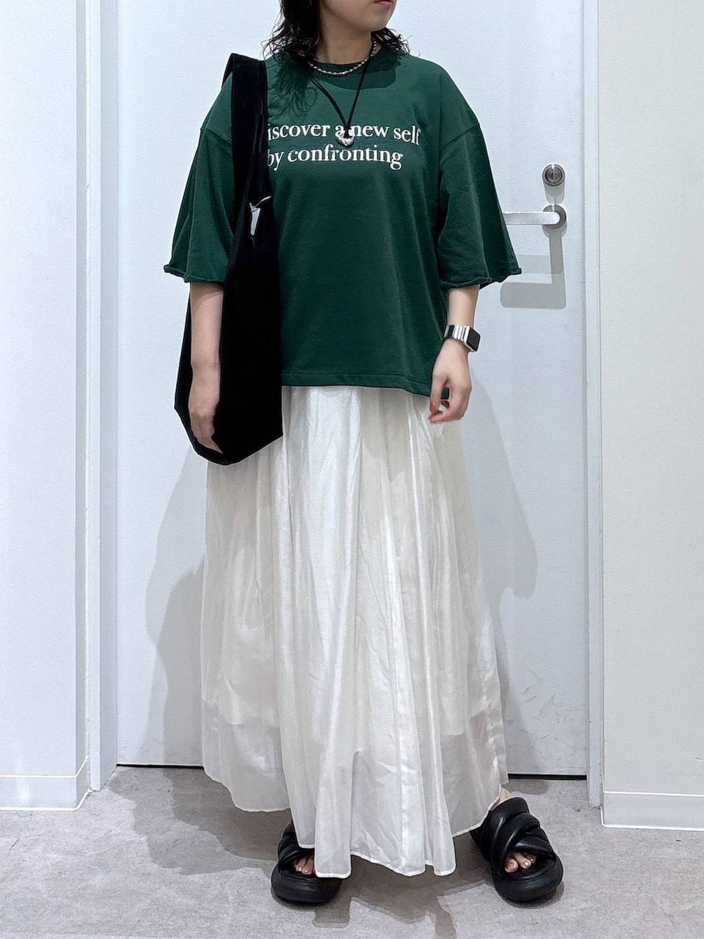 ベージュ系のスカート、ブラック系のトートバッグ、グリーン系のTシャツ/カットソーを着用したレディースの夏コーディネートの4枚目の写真