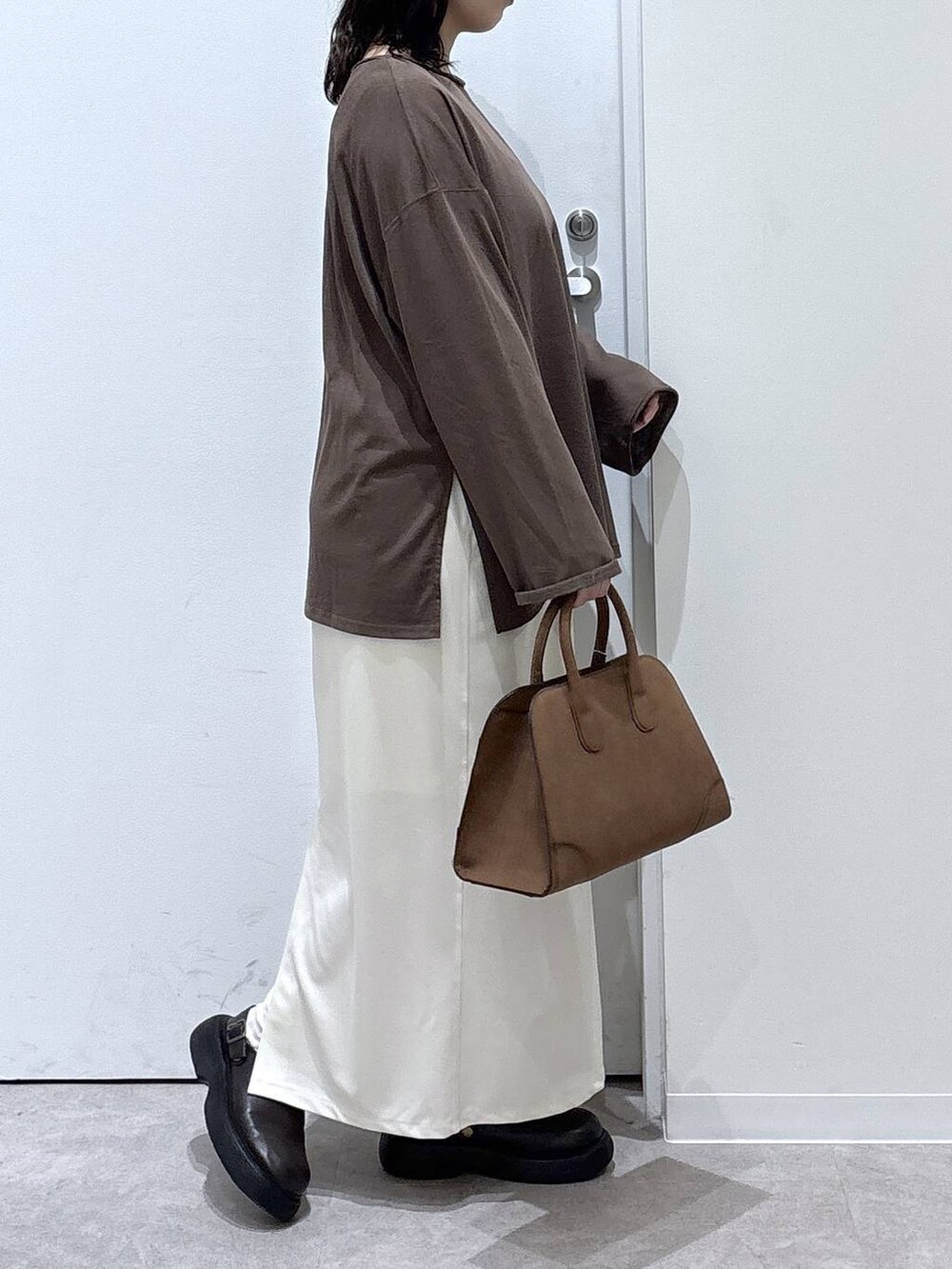 ベージュ系のショルダーバッグ、ベージュ系のスカート、ブラウン系のTシャツ/カットソーを着用したレディースの秋コーディネートの2枚目の写真