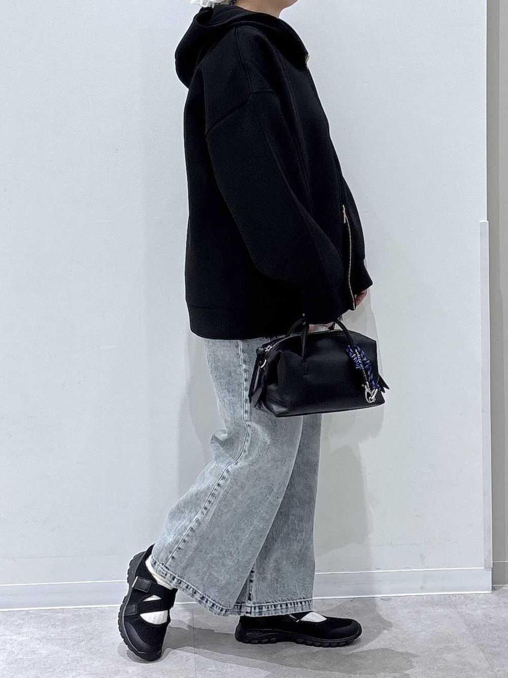 ブラック系のスニーカー、ブルー系のデニムパンツ、ブラック系のパーカーを着用したレディースの春コーディネートの2枚目の写真