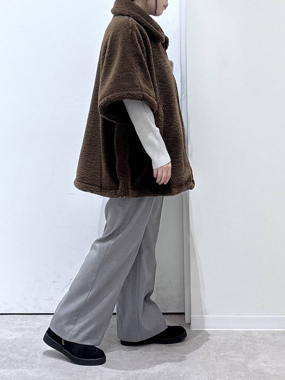 ベージュ系のニット/セーター、グレー系のその他パンツ、ブラウン系のポンチョを着用したレディースの秋コーディネートの2枚目の写真