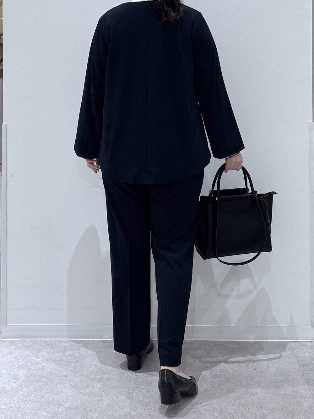 ブラック系のパンプス、ブルー系のセットアップ、ブラック系のトートバッグを着用したレディースの冬コーディネートの3枚目の写真