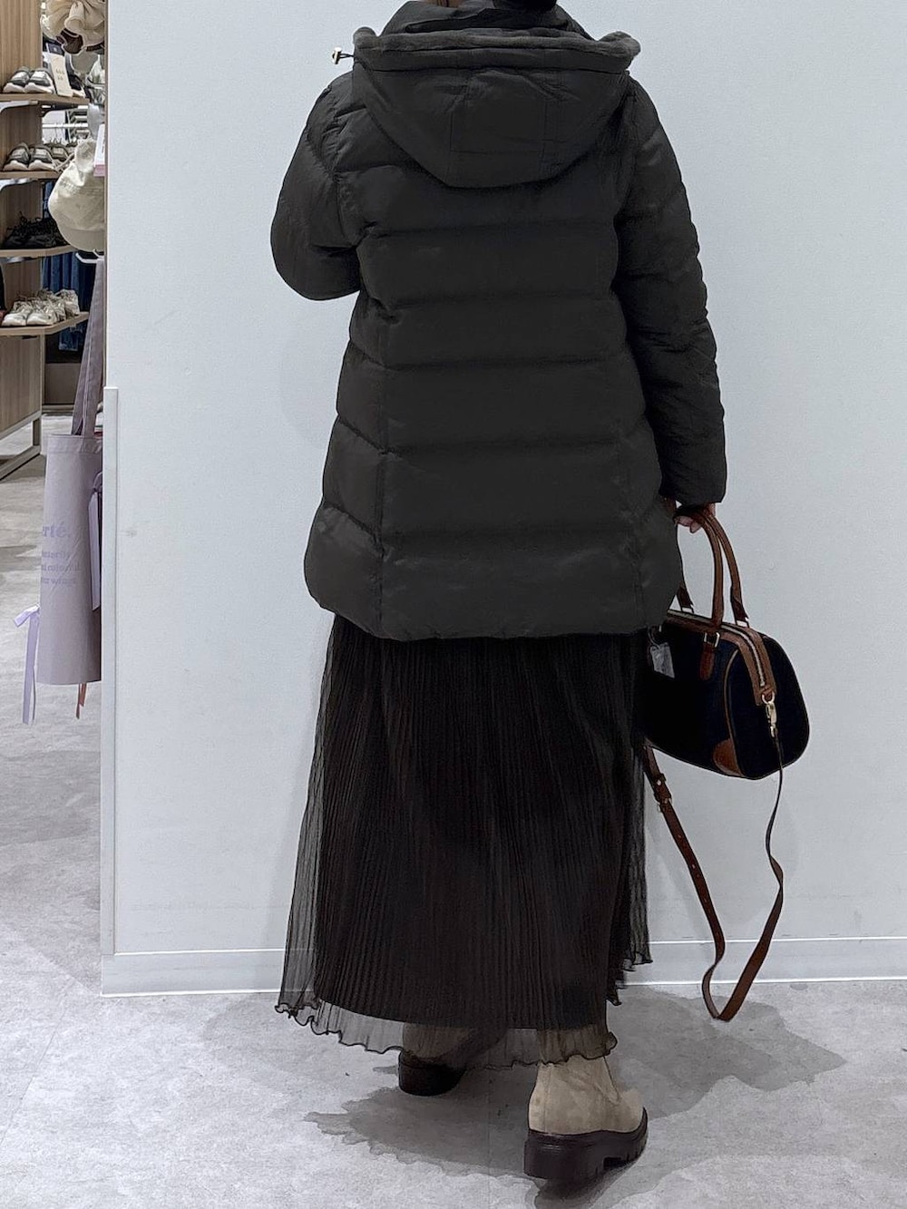 ブラウン系のダウンジャケット/コート、ベージュ系のブーツ、ブラック系のボストンバッグを着用したレディースの冬コーディネートの3枚目の写真