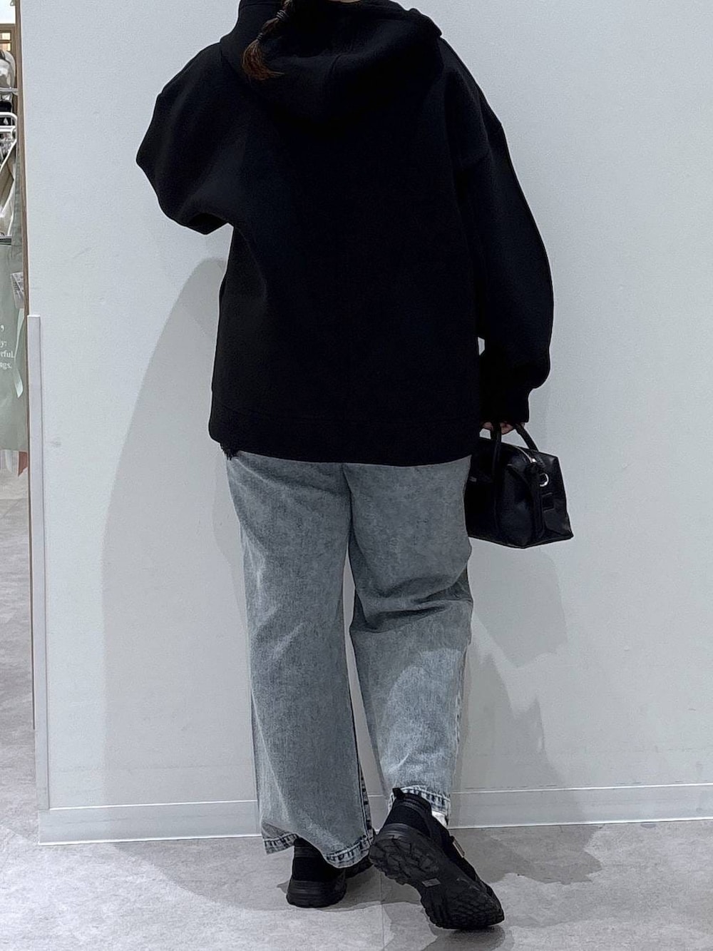 ブラック系のスニーカー、ブルー系のデニムパンツ、ブラック系のパーカーを着用したレディースの春コーディネートの3枚目の写真