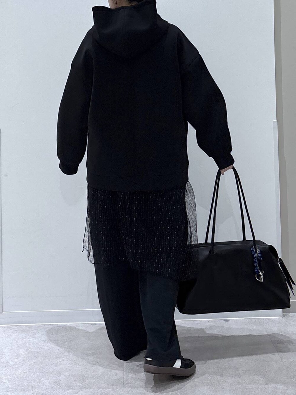 ブラック系のスニーカー、ブラック系のスウェットパンツ、ブラック系のパーカーを着用したレディースの冬コーディネートの3枚目の写真