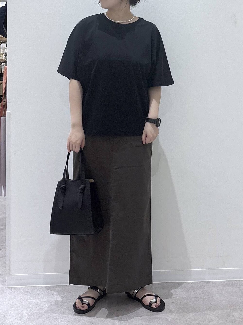 ブラック系のショルダーバッグ、ブラウン系のスカート、ブラック系のTシャツ/カットソーを着用したレディースの夏コーディネートの3枚目の写真