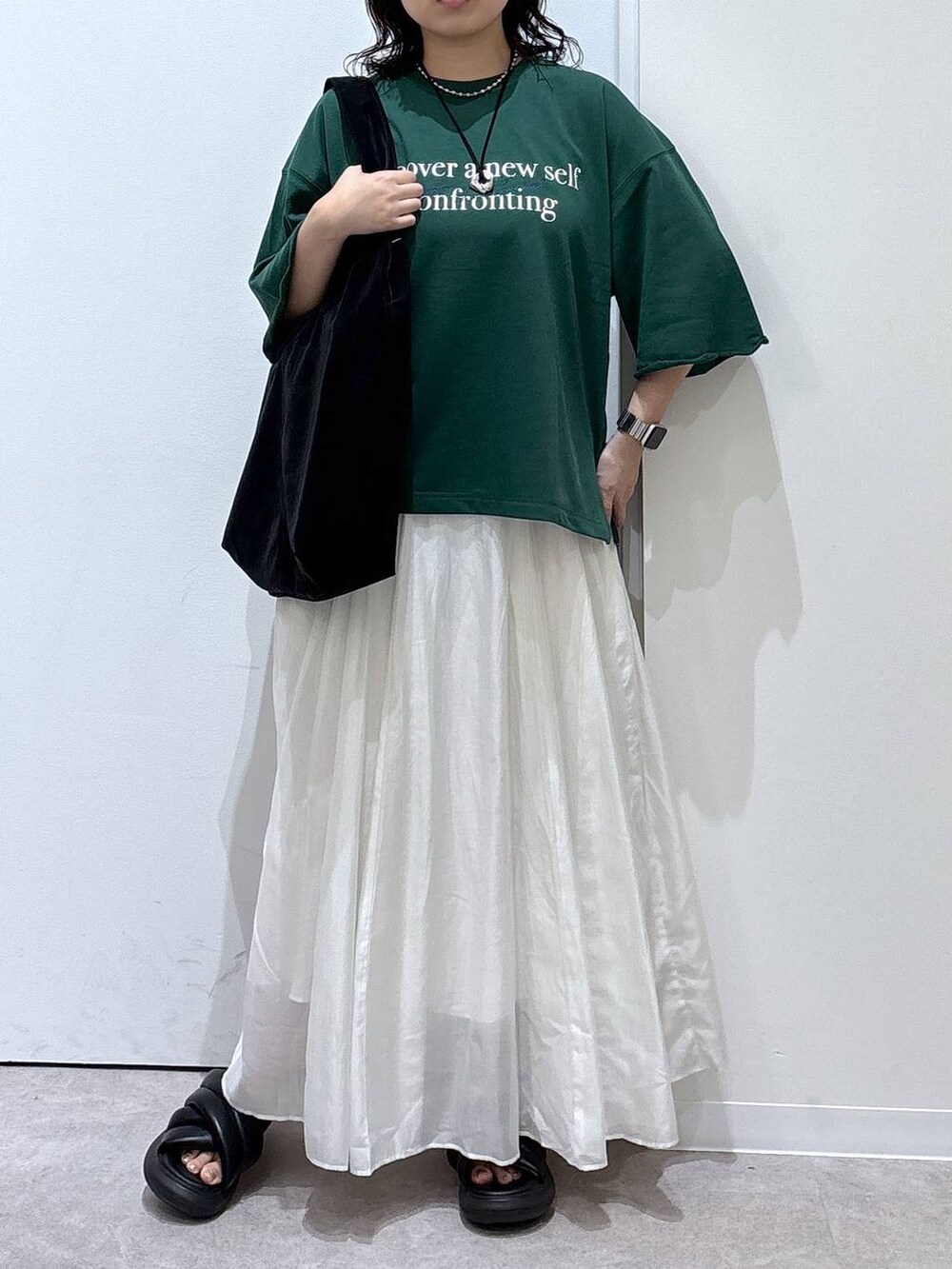 ベージュ系のスカート、ブラック系のトートバッグ、グリーン系のTシャツ/カットソーを着用したレディースの夏コーディネートの3枚目の写真