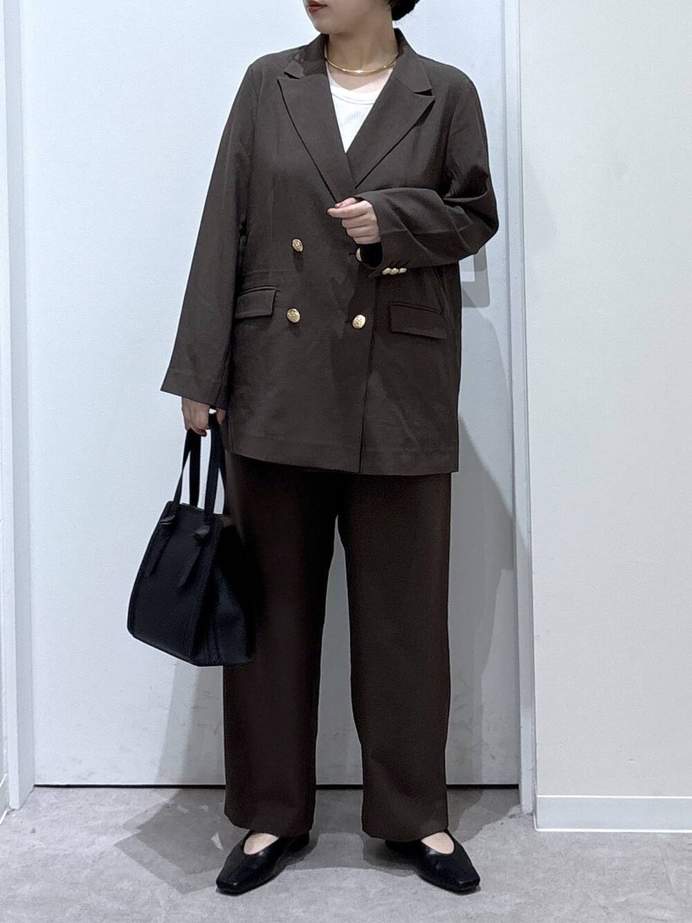 ブラック系のショルダーバッグ、ブラウン系のテーラードジャケット、ブラウン系のスラックスを着用したレディースの秋コーディネートの4枚目の写真
