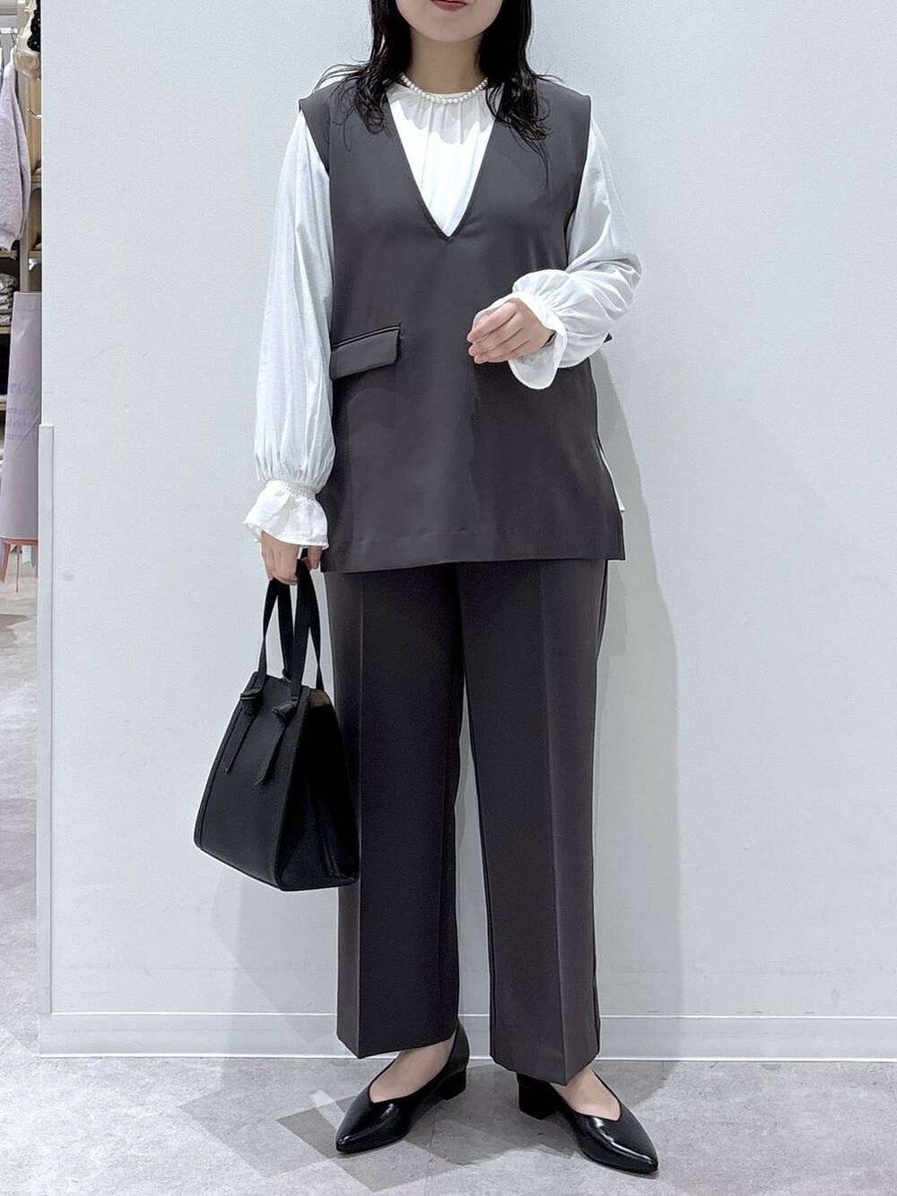 ブラック系のショルダーバッグ、ブラック系のパンプス、グレー系のセットアップを着用したレディースの冬コーディネートの4枚目の写真