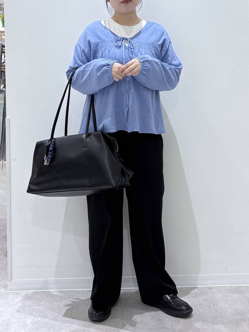ブラック系のボストンバッグ、ブラック系のスラックス、ブルー系のカーディガン/ボレロを着用したレディースの春コーディネートの3枚目の写真