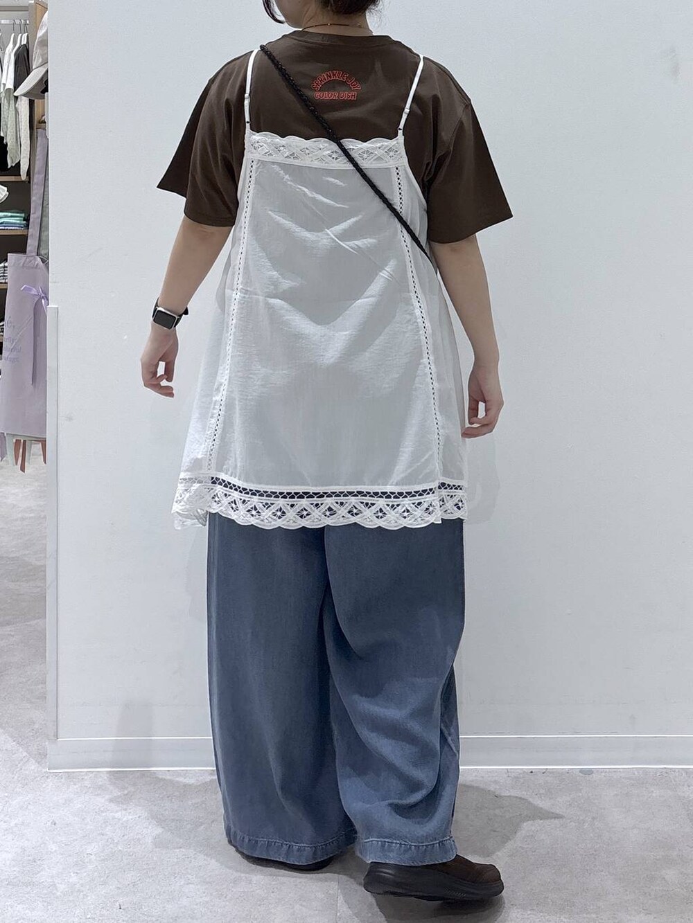 ブラウン系のTシャツ/カットソー、ブラウン系のスニーカー、ブルー系のデニムパンツを着用したレディースの春コーディネートの3枚目の写真