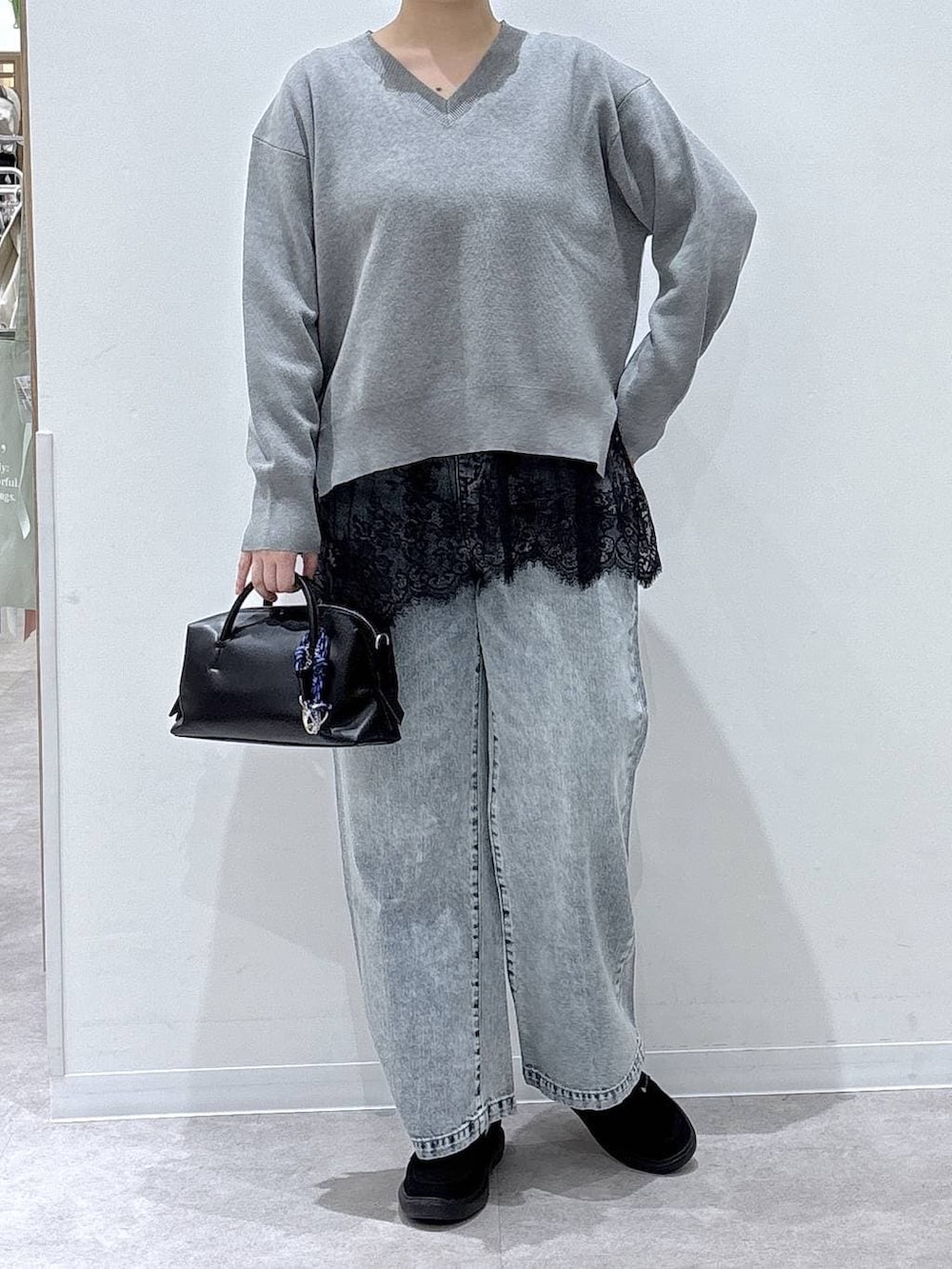 ブルー系のデニムパンツ、グレー系のニット/セーター、ブラック系のスニーカーを着用したレディースの春コーディネートの3枚目の写真