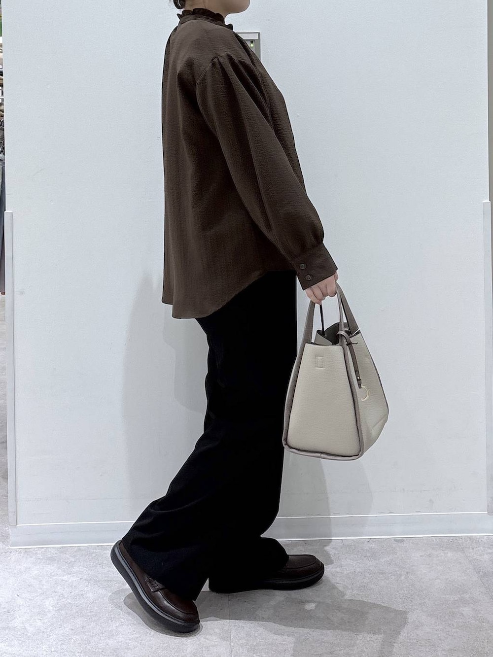 ベージュ系のトートバッグ、ブラック系のスラックス、ブラウン系のシャツ/ブラウスを着用したレディースの春コーディネートの2枚目の写真