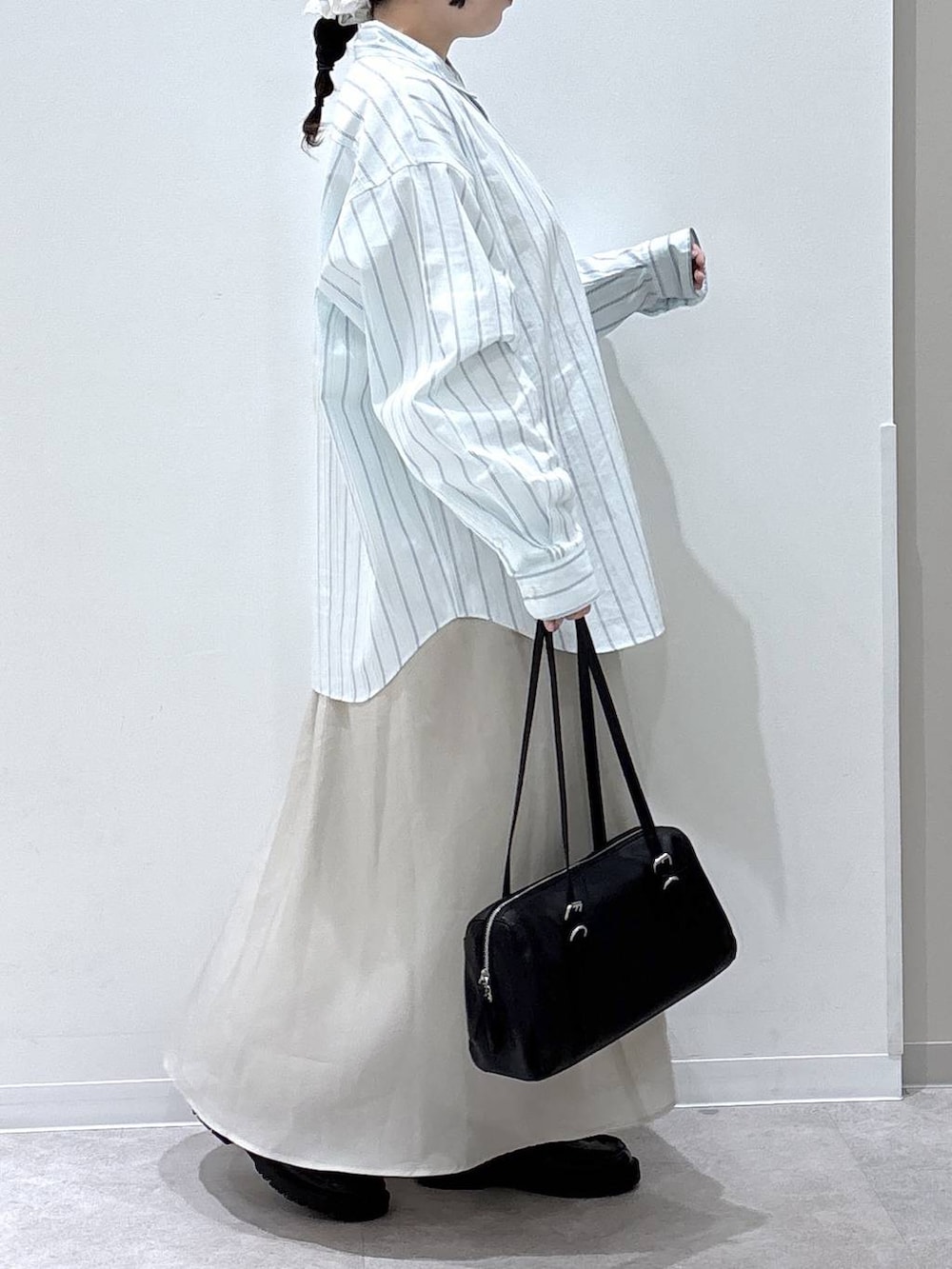 ベージュ系のスカート、ブラック系のショルダーバッグ、ブルー系のシャツ/ブラウスを着用したレディースの春コーディネートの2枚目の写真