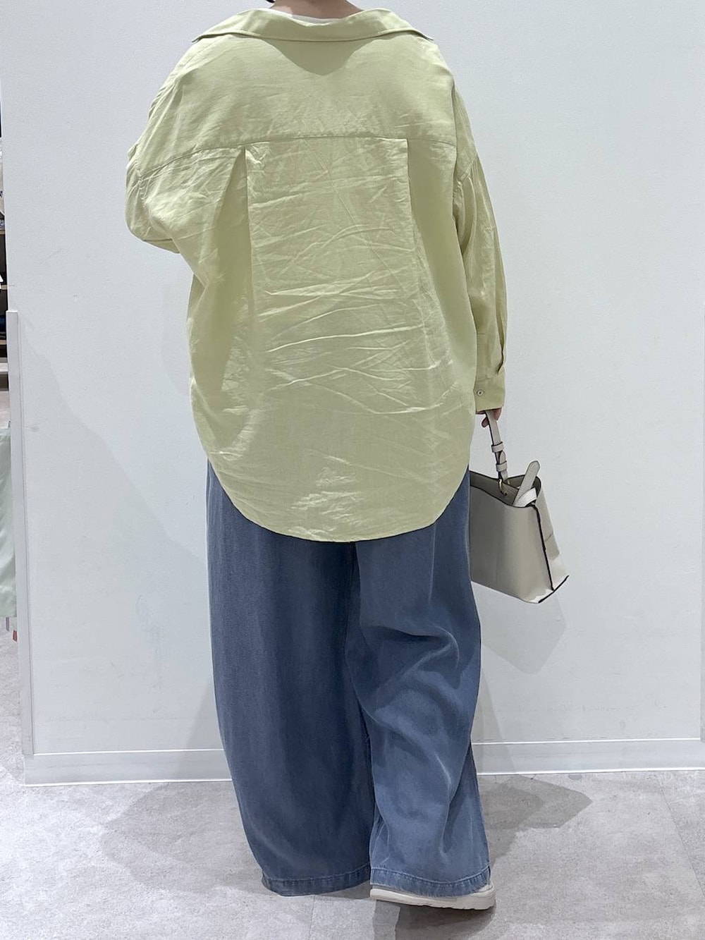 イエロー系のシャツ/ブラウス、ベージュ系のショルダーバッグ、ブルー系のデニムパンツを着用したレディースの春コーディネートの3枚目の写真