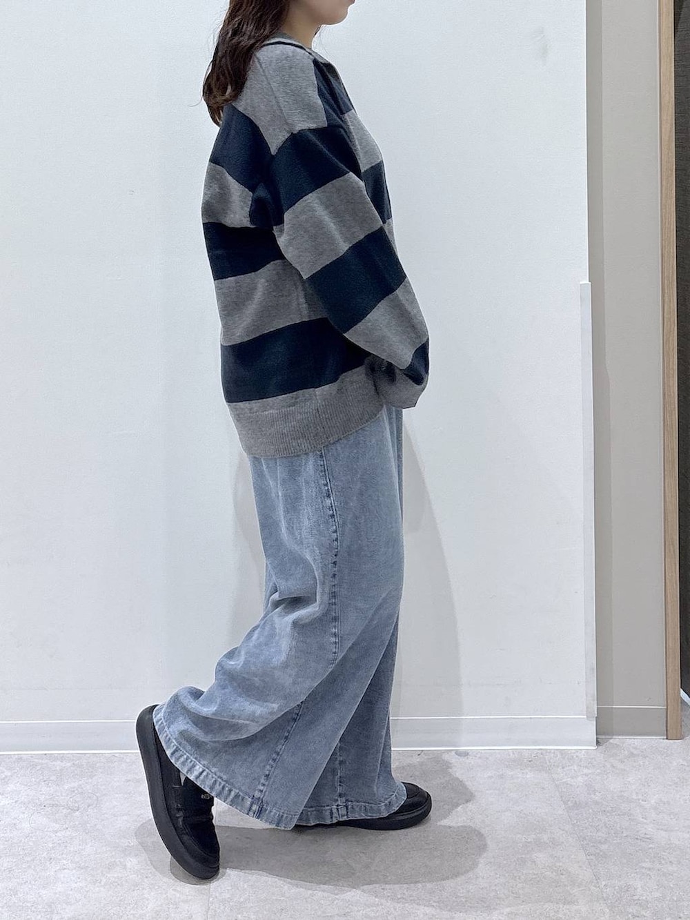ブラック系のローファー、グレー系のニット/セーター、ブルー系のデニムパンツを着用したレディースの秋コーディネートの2枚目の写真