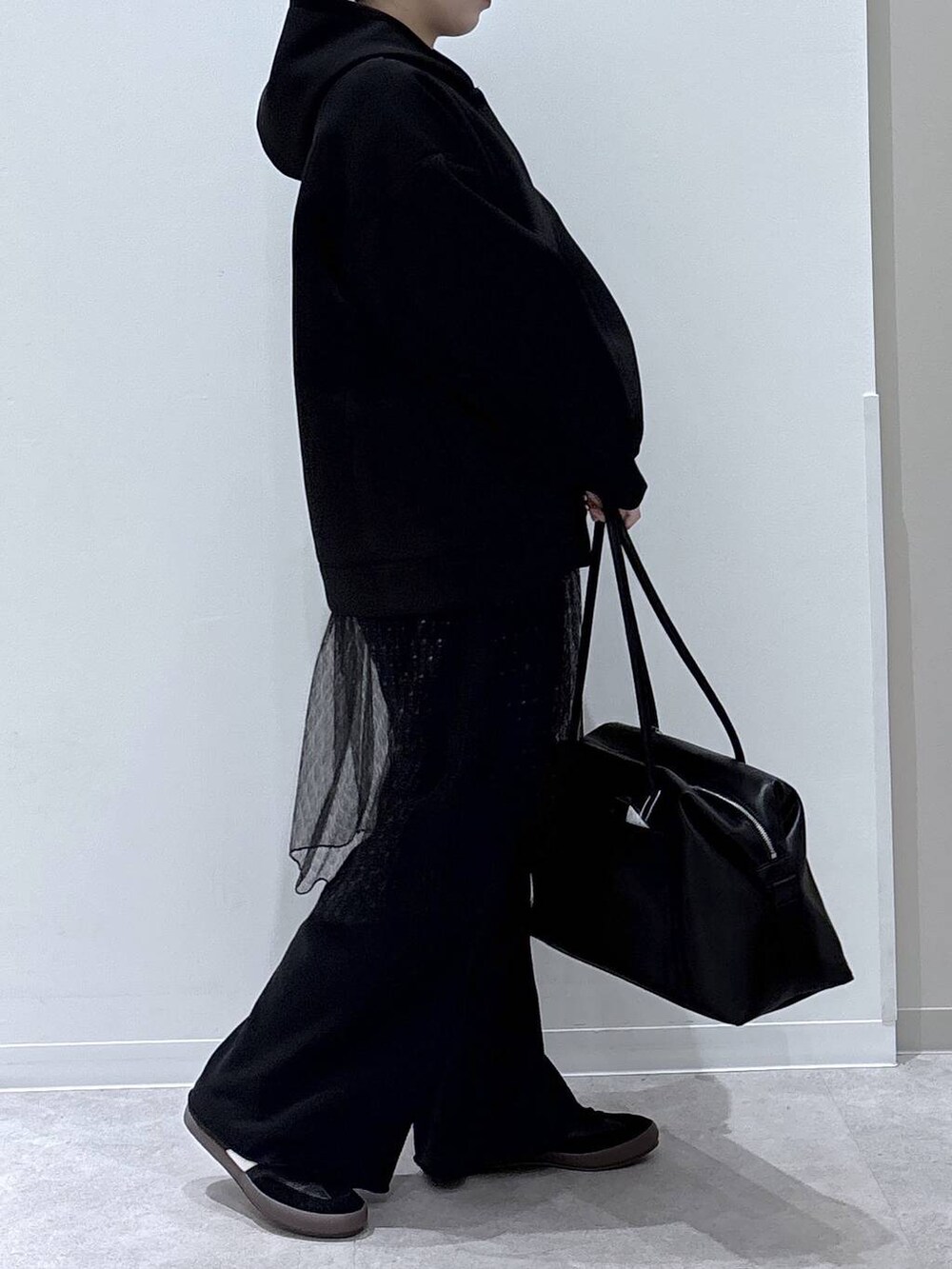 ブラック系のスニーカー、ブラック系のスウェットパンツ、ブラック系のパーカーを着用したレディースの冬コーディネートの2枚目の写真