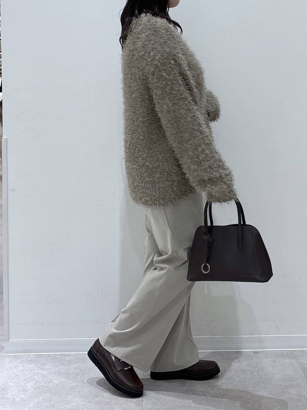 ブラウン系のローファー、ブラウン系のショルダーバッグ、ベージュ系のスラックスを着用したレディースの冬コーディネートの2枚目の写真