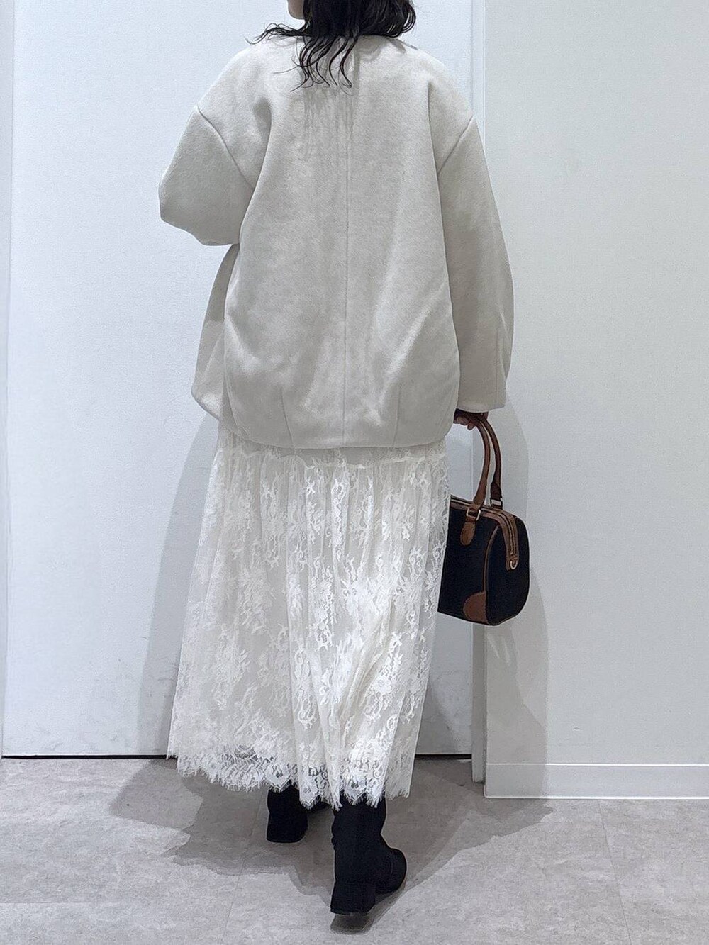 ベージュ系のノーカラーコート、グレー系のワンピース、ブラック系のボストンバッグを着用したレディースの秋コーディネートの3枚目の写真