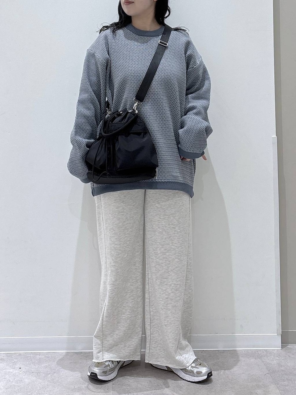ブラック系のショルダーバッグ、ホワイト系のスウェットパンツ、ブルー系のニット/セーターを着用したレディースの冬コーディネートの4枚目の写真