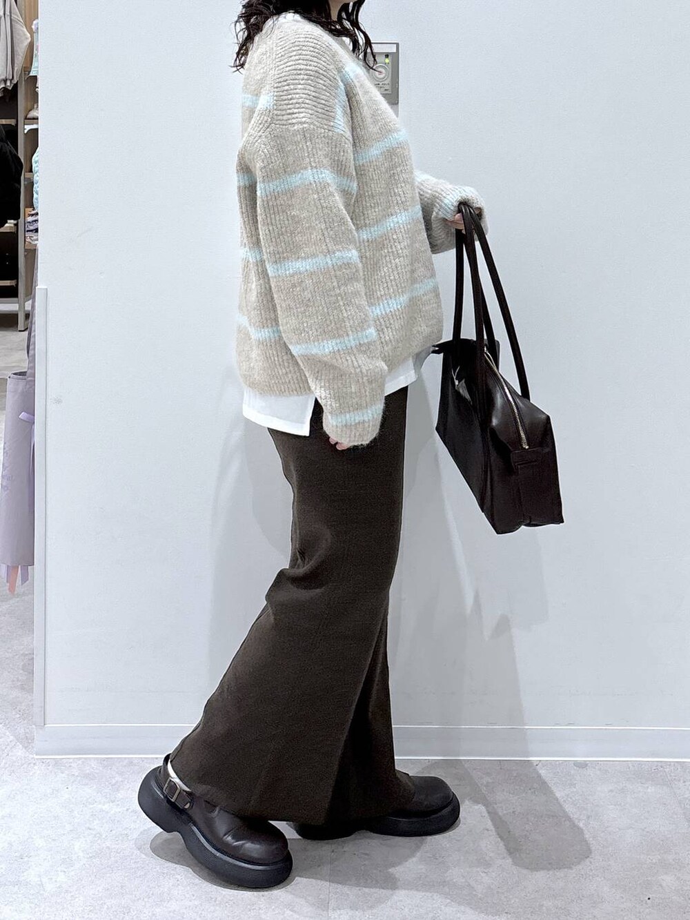 ブラウン系のボストンバッグ、ホワイト系のTシャツ/カットソー、ベージュ系のニット/セーターを着用したレディースの秋コーディネートの2枚目の写真