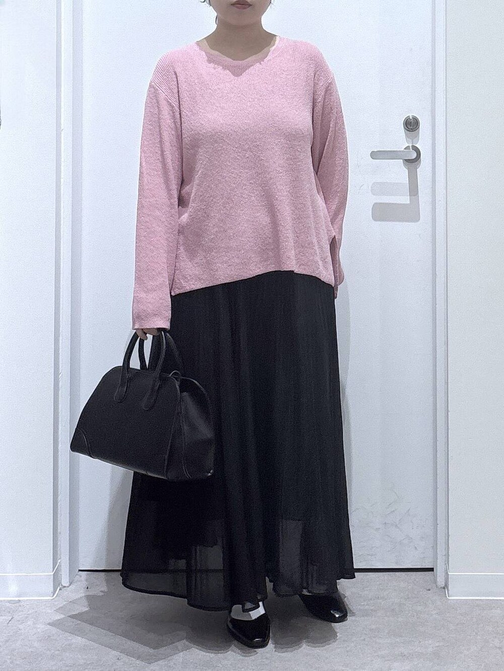 ブラック系のパンプス、ブラック系のスカート、ピンク系のニット/セーターを着用したレディースの秋コーディネートの4枚目の写真